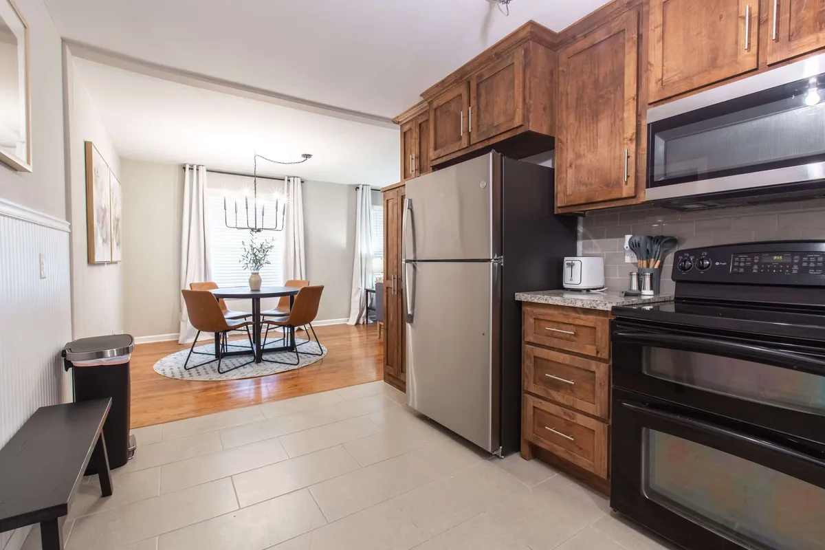 An open-plan kitchen area with prominent appliances, wooden cabinetry, and a view of the adjoining dining space. The setup highlights the connection between meal preparation and gathering spaces, ideal for hosting or family traditions.