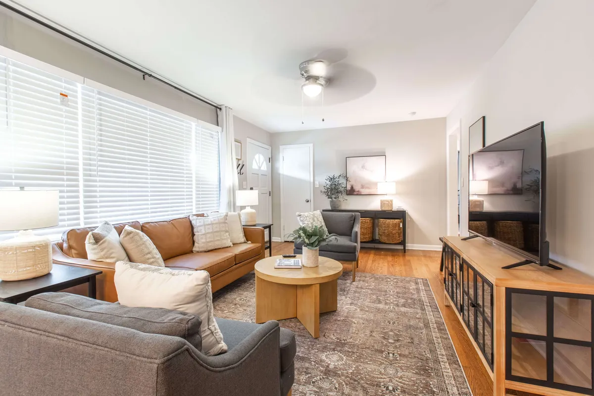 A comfortable living room scene showcasing two sofas, a coffee table, a wall-mounted television, and curated artwork. The space invites both relaxation and entertainment, with thoughtful lighting and a layout ideal for intimate gatherings or a solo unwind after a busy day.