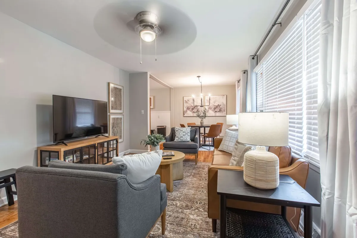 An inviting interior view with a sofa, coffee table, television, and a well-defined dining area, all bathed in soft lighting. The setup is perfect for relaxing, reading, or socializing, and the open layout ensures a comfortable environment for both work and leisure.